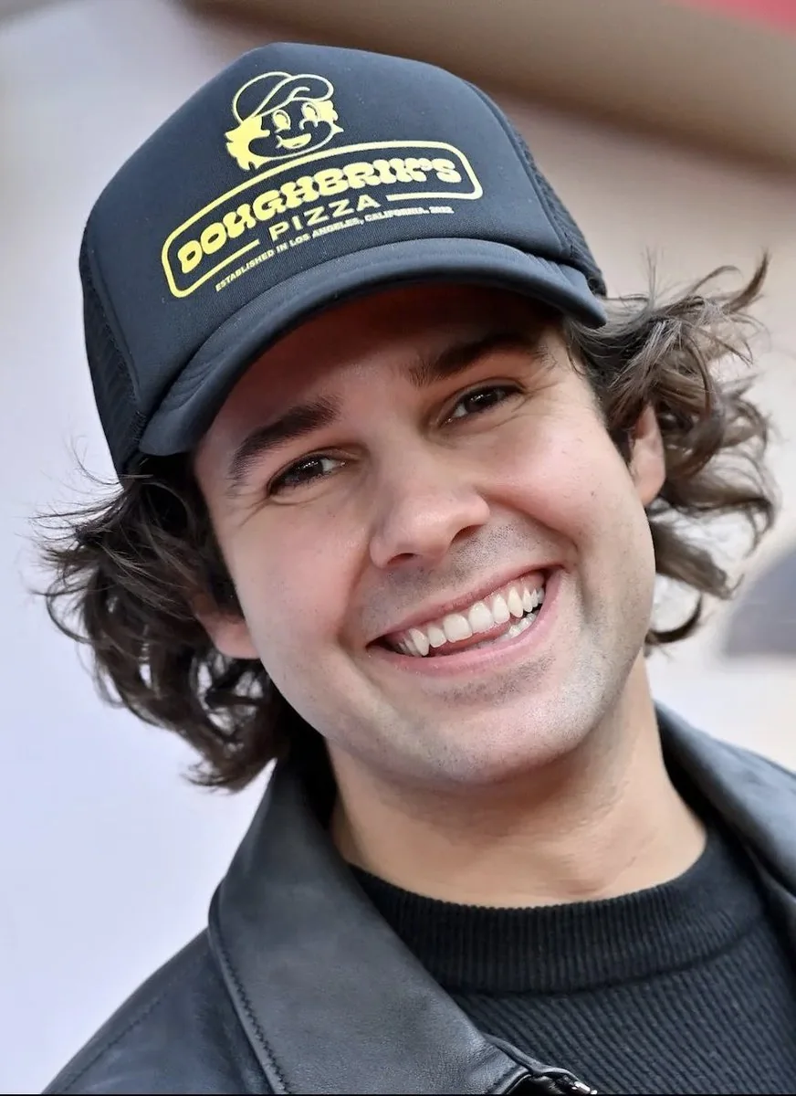 David Dobrik in a Doughbrik's Pizza hat smiling at camera